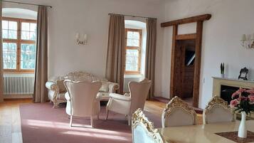 A room with a dining table, chairs, a fireplace, and large windows with curtains.