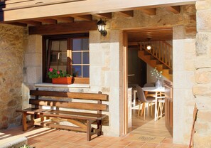A stone exterior with a wooden bench, a window with a potted plant, and a staircase leading to an interior dining area. - Casa Celis 2, for 4 people in Espinareu (La Villa)