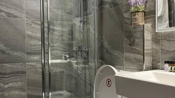 Une salle de bain moderne avec une douche à parois de verre, des toilettes blanches et un mur recouvert de carreaux de marbre.