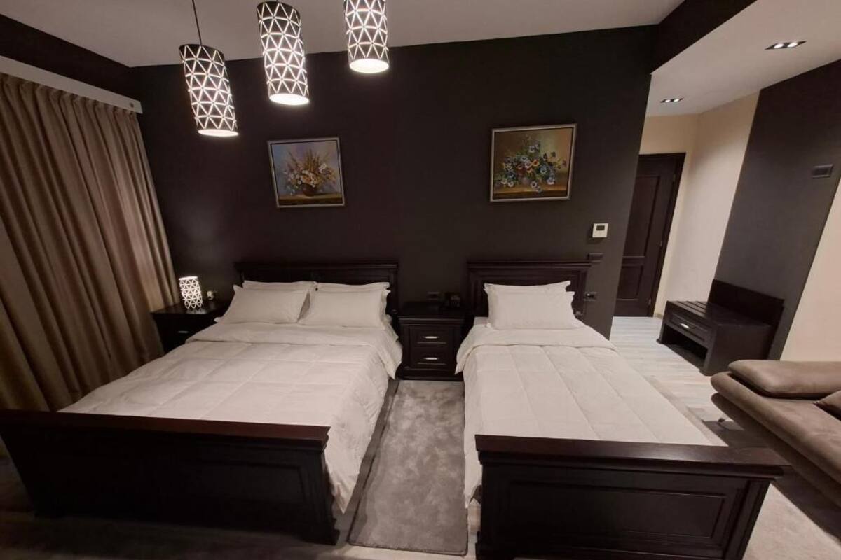 Un dormitorio con dos camas, un sofá y lámparas colgantes.