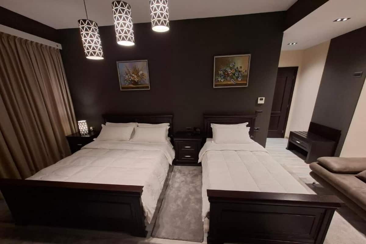 Une chambre avec deux lits, un canapé et des lampes suspendues.