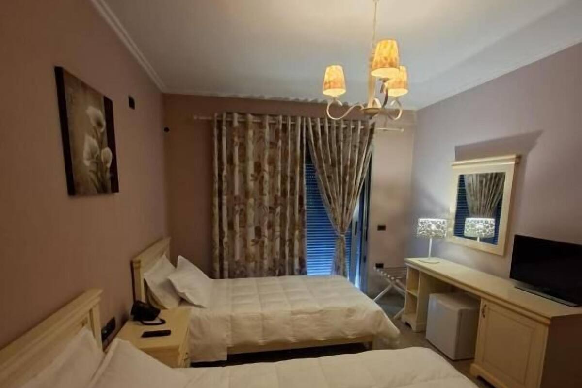 Habitación de hotel con dos camas, un escritorio, un televisor y un candelabro.
