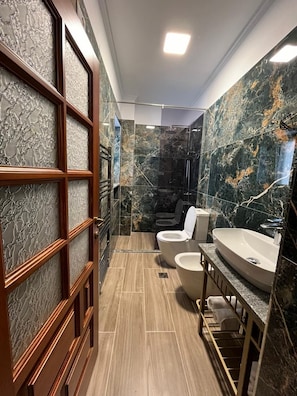 A modern bathroom with a wooden vanity, a freestanding toilet, and a bathtub.