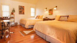 Ein Zimmer mit zwei Betten, einem Schreibtisch, einem Stuhl und einer Zimmerpflanze.
