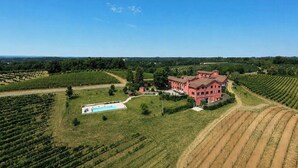 A large pink building surrounded by green fields and a swimming pool.