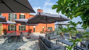 A terrace with outdoor furniture, umbrellas, and a stone floor.