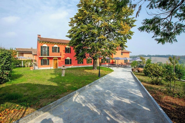 A red building with a paved pathway leading to a covered outdoor seating area.