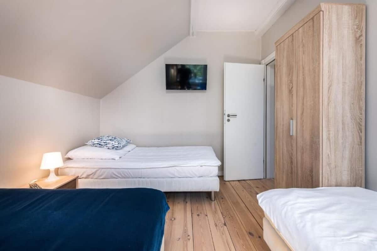 A bedroom with a bed, a bedside table with a lamp, a wardrobe, and a framed picture on the wall.