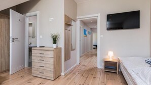 A bedroom with a bed, bedside table, and a TV mounted on the wall.