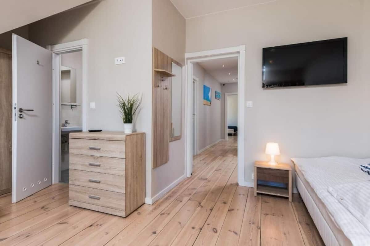 A bedroom with a bed, bedside table, and a TV mounted on the wall.