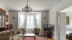 A living room with a sofa, armchair, TV, and a chandelier. - Grand Belle Sopot - Near the beach (Sopot)