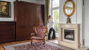 A room with a large wooden wardrobe, a tufted armchair, a fireplace, and a large mirror. - Grand Belle Sopot - Near the beach (Sopot)