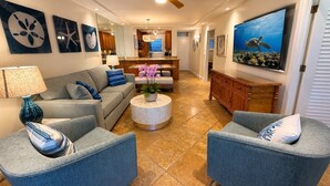 Een woonkamer met een bank, fauteuils, een salontafel en een televisie.