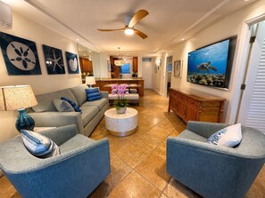 Ein Wohnzimmer mit einer Couch, Sesseln, einem Couchtisch und einem Fernseher.