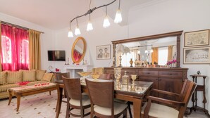 A dining area with a wooden table and chairs, a sofa, a TV, and a large mirror. - Amalia Country House (Zakynthos)