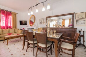 A dining area with a wooden table and chairs, a sofa, a TV, and a large mirror. - Amalia Country House (Zakynthos)