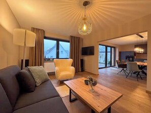 Ein modernes Wohnzimmer mit Sofa, Sesseln und Essbereich.