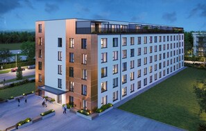 Ein modernes Mehrstöckhotel mit flachem Dach, großen Fenstern und einem begrünten Innenhof.