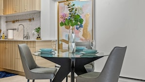 Un espace repas moderne avec une table en verre, deux chaises grises et un vase rempli de fleurs.