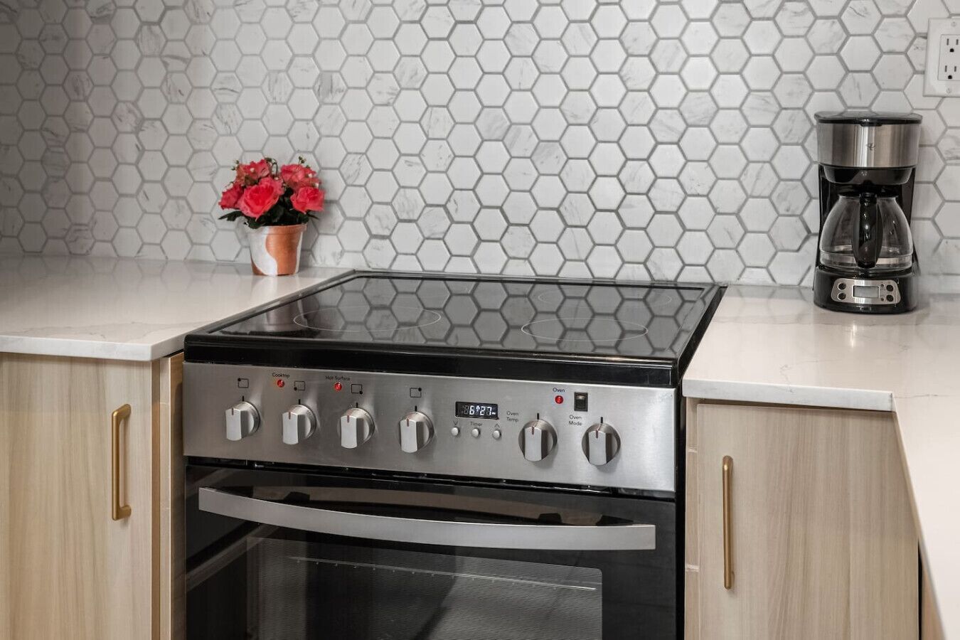 A kitchen with a gas stove, oven, and a coffee maker on the countertop.