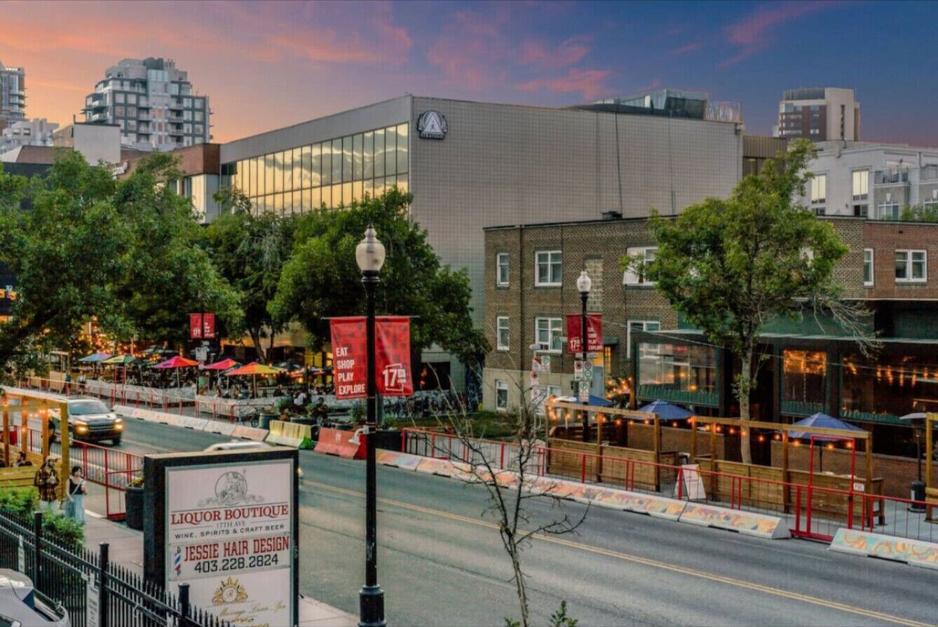 A building with a large glass facade, a sign for a liquor boutique, and outdoor seating with umbrellas.