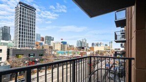 Un balcon offrant une vue sur le paysage urbain, avec de hauts immeubles et une rue.
