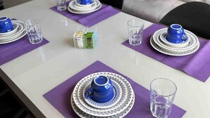 A dining table set with blue and white plates, glasses, and a small box of tea. - LK Barro Preto 10 (Belo Horizonte)