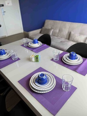 A dining table set with blue and white plates, glasses, and a small box of tea. - LK Barro Preto 10 (Belo Horizonte)