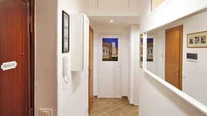 Un couloir avec une porte en bois portant l’inscription « PHOTOGRAPHIE », un téléphone blanc fixé au mur et des tableaux encadrés.