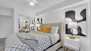 A bedroom with a bed, bedside table, lamp, and abstract wall art. - 17th Ave Nest in Downtown , Walk to Stampede Grounds (Calgary)