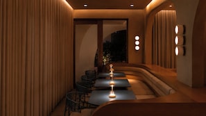 A modern interior with a curved bench seating area, a small table, and a wall-mounted lamp.
