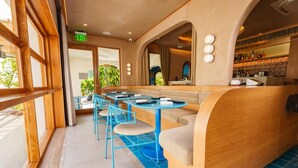 A restaurant with a long counter, blue chairs, and a seating area with a bench.