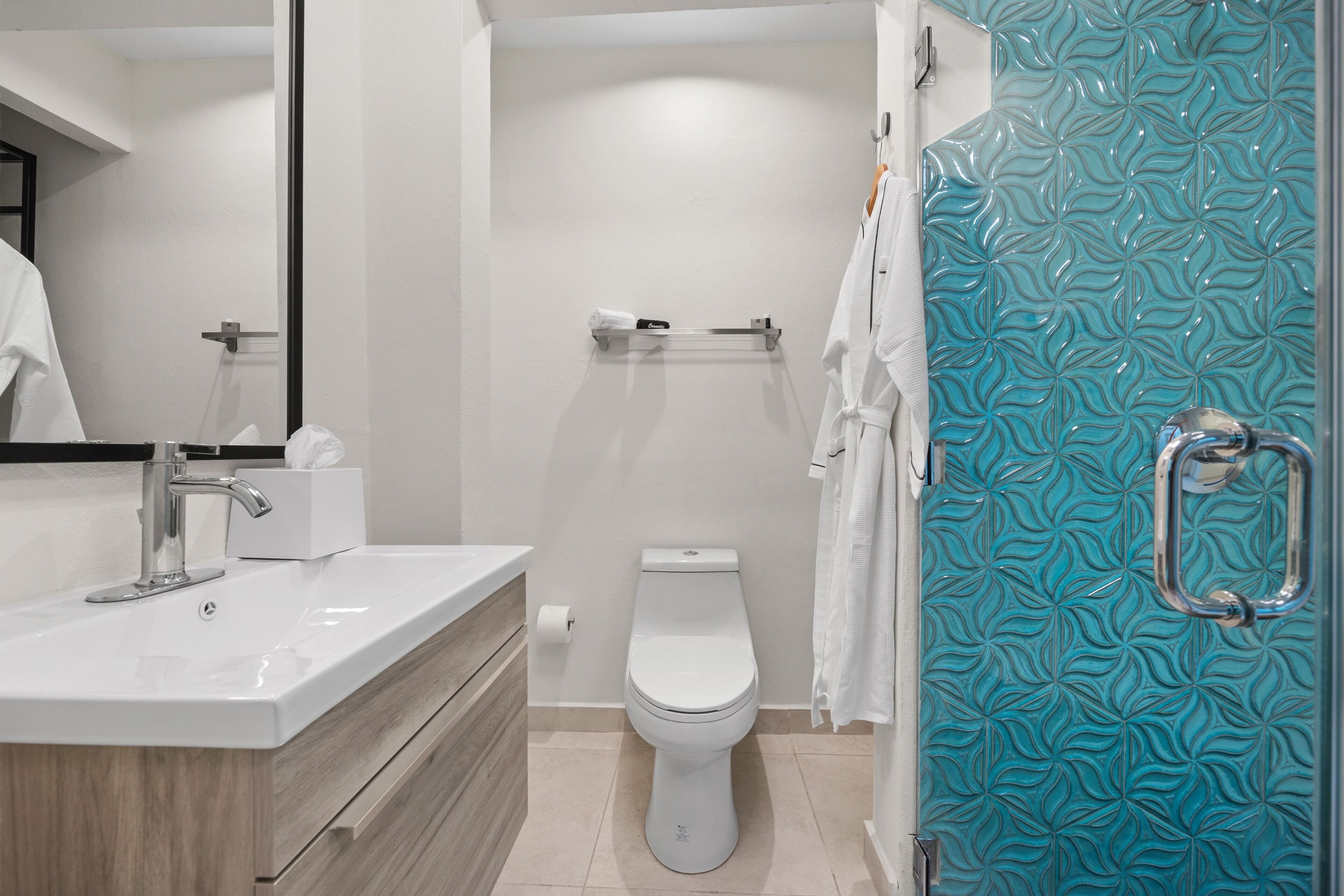A modern bathroom with a white toilet, a sink with a mirror, and a shower area with a patterned glass door.