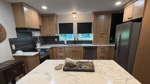 Una cocina moderna con una isla de mármol, armarios de madera y un refrigerador de acero inoxidable.
