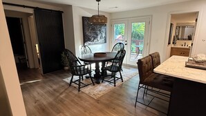 Un comedor con una mesa y sillas de madera, un candelabro y vistas a través de puertas de cristal.