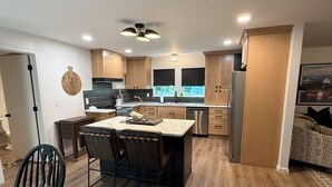 Una cocina moderna con armarios de madera, una isla central y un comedor con mesa y sillas.