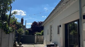 Un patio con mobiliario exterior, una mesa de vidrio y vistas al cielo.