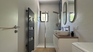 Un baño moderno con ducha, lavamanos y espejo.