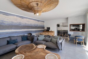 A modern living room with a sectional sofa, a wooden coffee table, and a large abstract wall mural. - Villa la Chiappa: Seaside, Heated Pool & Jacuzzi (Porto-Vecchio)