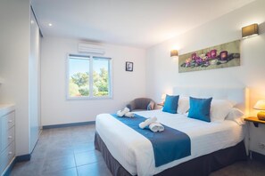 A hotel room with a bed, a chair, a desk, a window, and a painting on the wall. - Villa la Chiappa: Seaside, Heated Pool & Jacuzzi (Porto-Vecchio)
