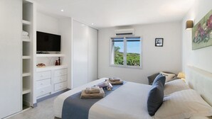 Un dormitorio con cama, televisión, ventana con vistas y armario.