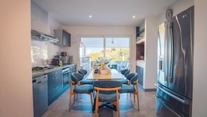 A modern kitchen with a dining area, stainless steel appliances, and a large window.