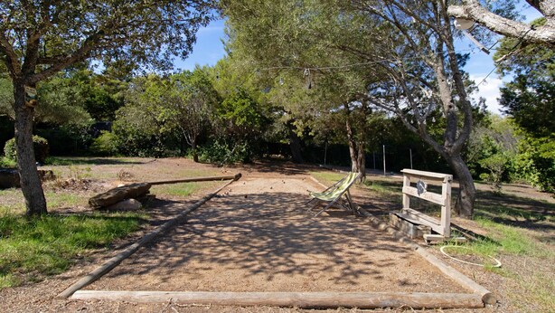 Un parque con un banco de madera, un cartel indicador y un sendero de tierra.
