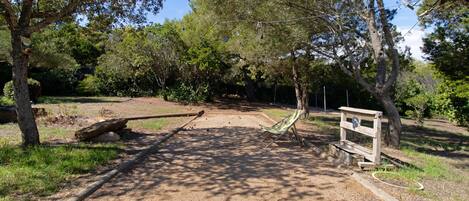 A park with a wooden bench, a signpost, and a dirt path.