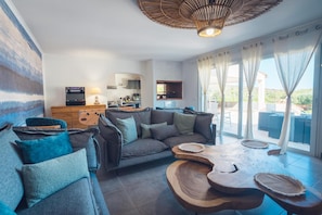 Een moderne woonkamer met een bank, salontafel en een keuken op de achtergrond.