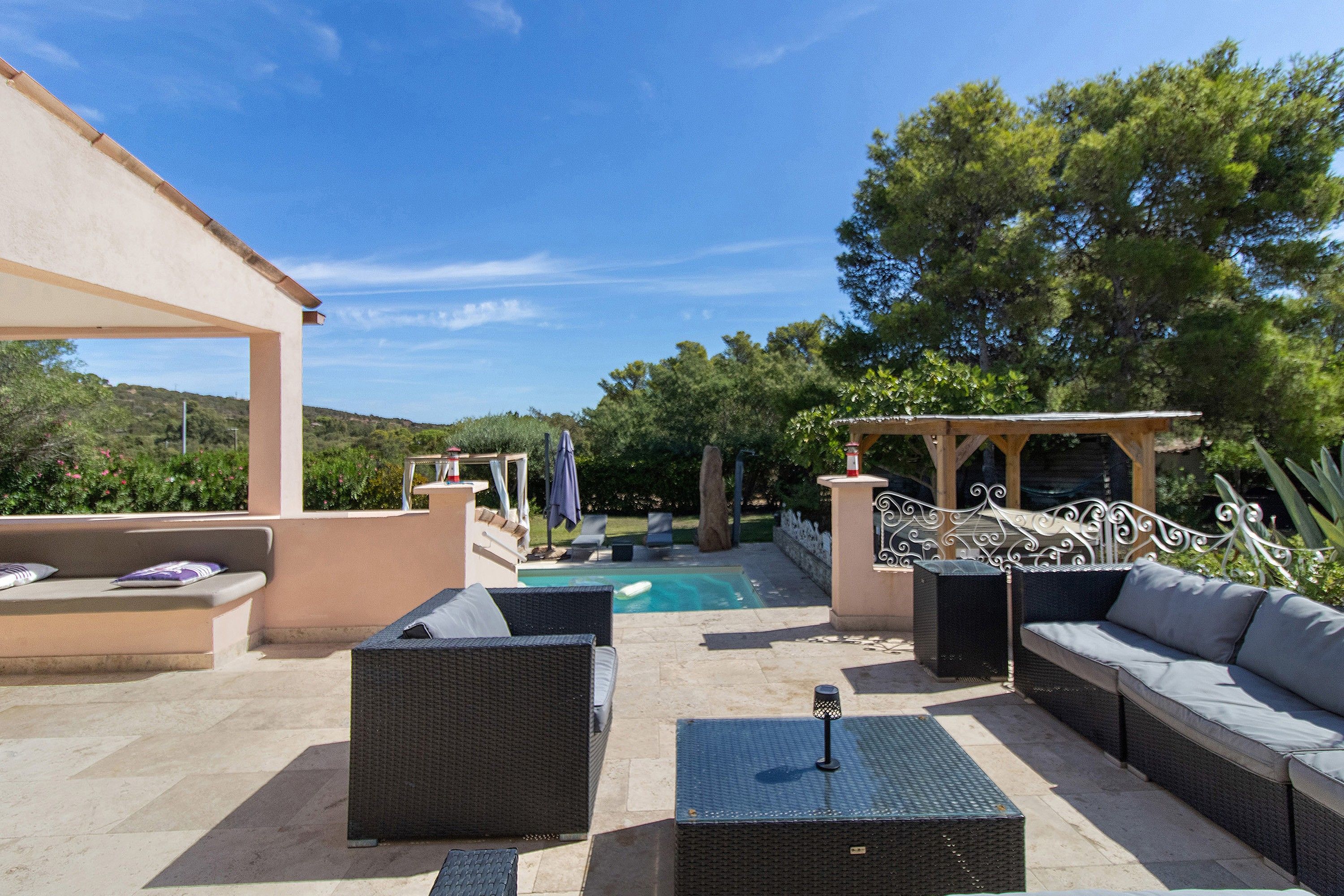 An outdoor patio with wicker furniture, a pool, and a pergola.