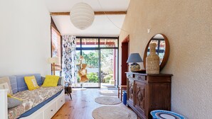 A room with a sofa, a cabinet, a mirror, and a view through a glass door. - Villa “Golf” with Shared Pool, Private Terrace, and Private Garden (Moliets-et-Maa)