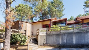 A rustic cabin with a wooden exterior, a concrete retaining wall, and a staircase leading to the entrance. - Villa “Golf” with Shared Pool, Private Terrace, and Private Garden (Moliets-et-Maa)