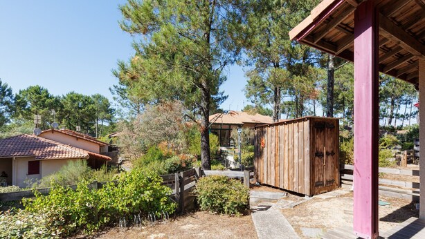 A rustic cabin with a tiled roof, surrounded by pine trees and a wooden fence. - Villa “Golf” with Shared Pool, Private Terrace, and Private Garden (Moliets-et-Maa)