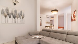 A modern living room with a sectional sofa, a framed botanical print, and pendant lighting.
